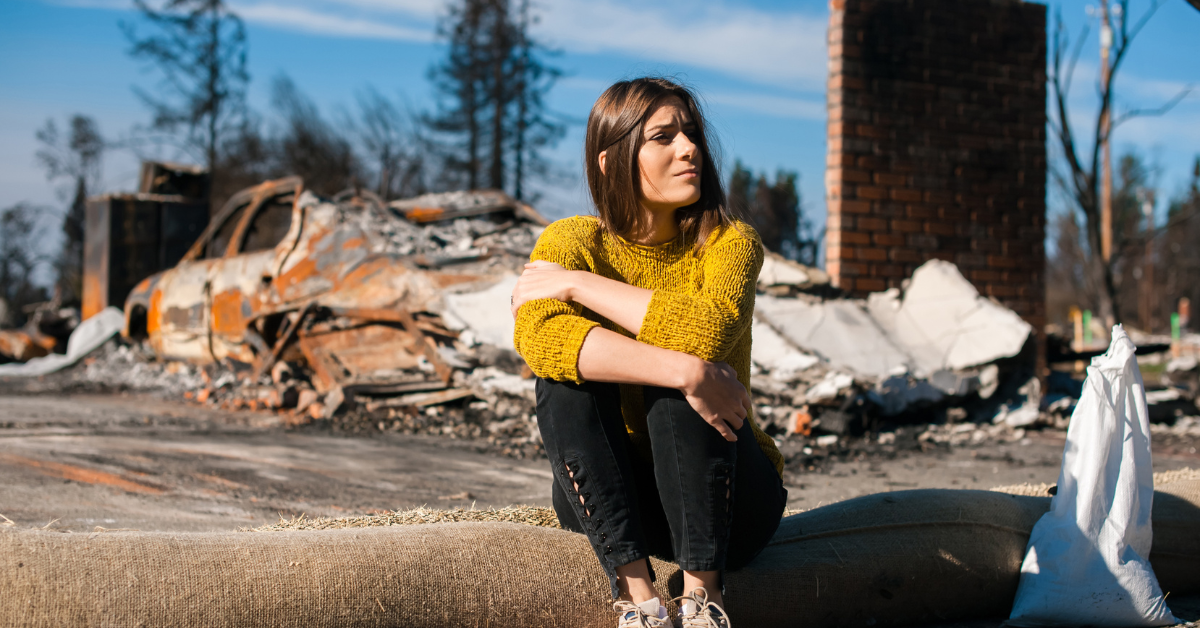 Woman sitting in front of storm damaged home