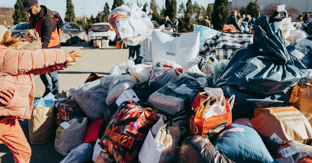 Child throwing bag of clothing donations into a huge pile of other bags