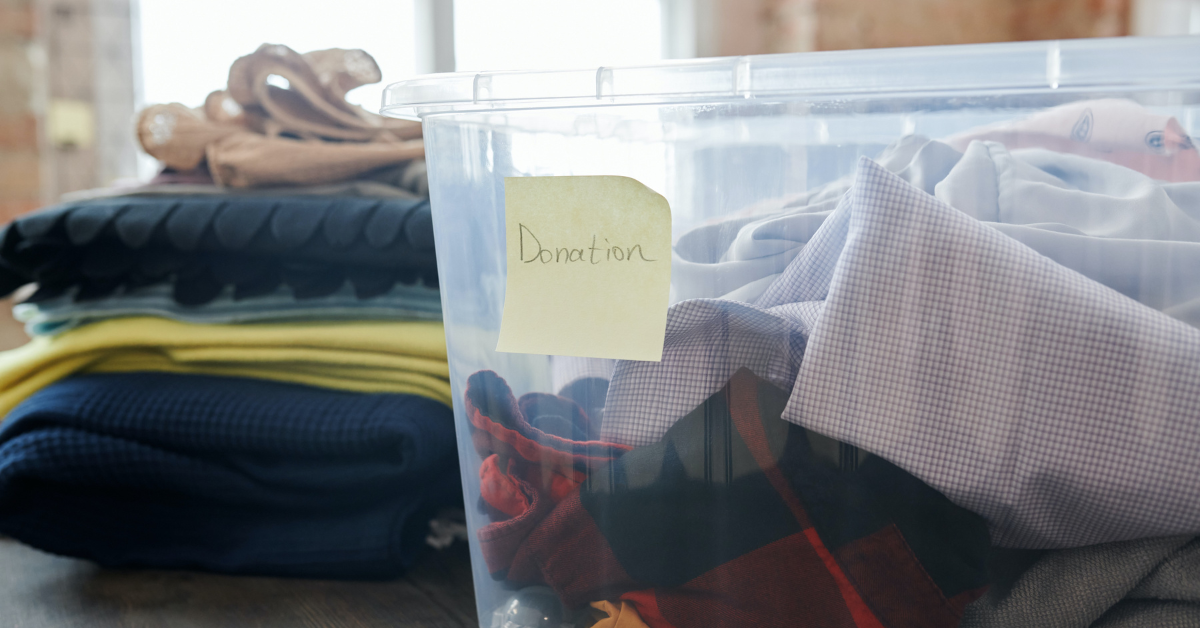 Clear bin of clothes with yellow sticky note reading donations